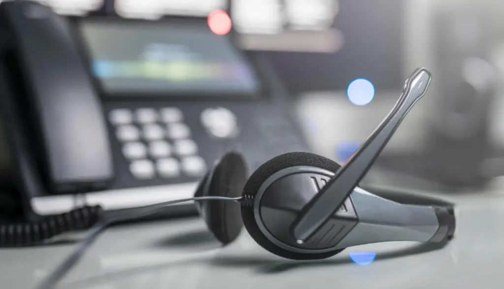 Closeup of a headset on a desk in front of a phone