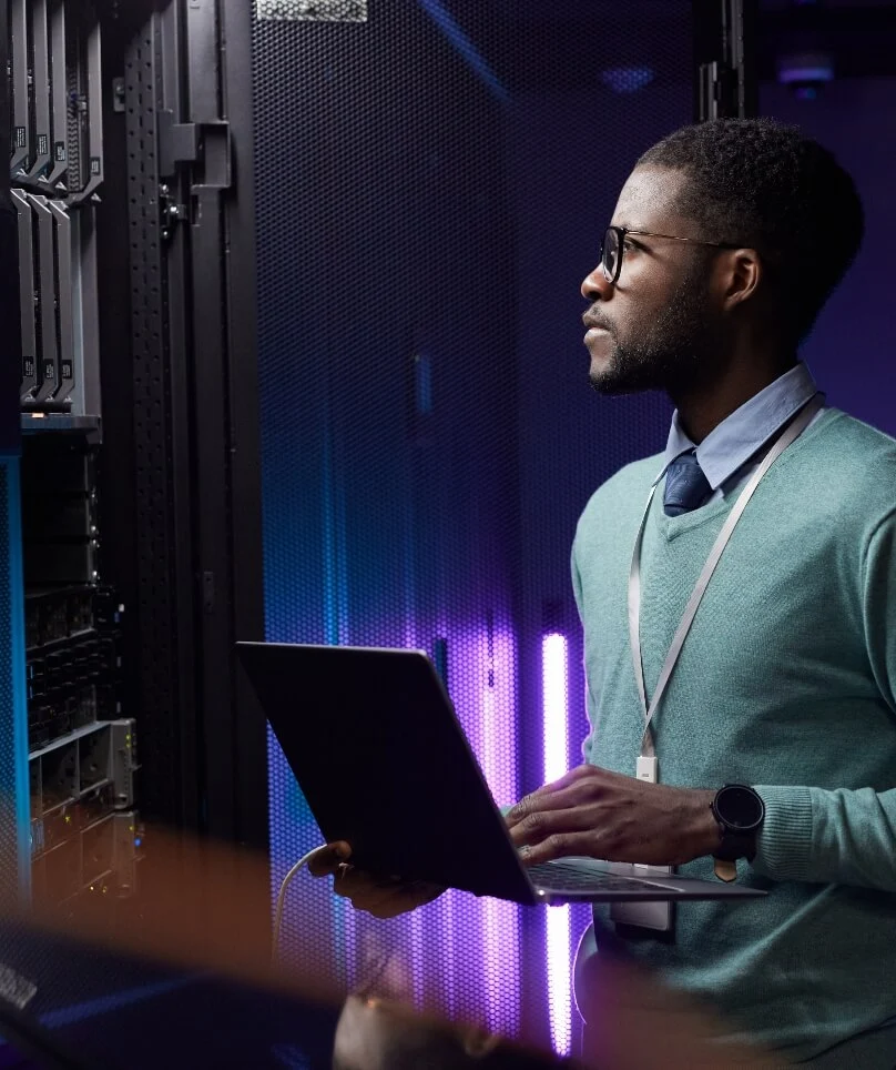 Sideview of a person holding a laptop and looking at servers