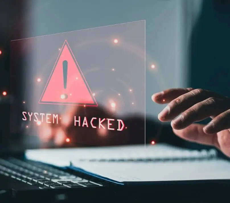 System hacked alert superimposed over a user's hands, keyboard and notebook