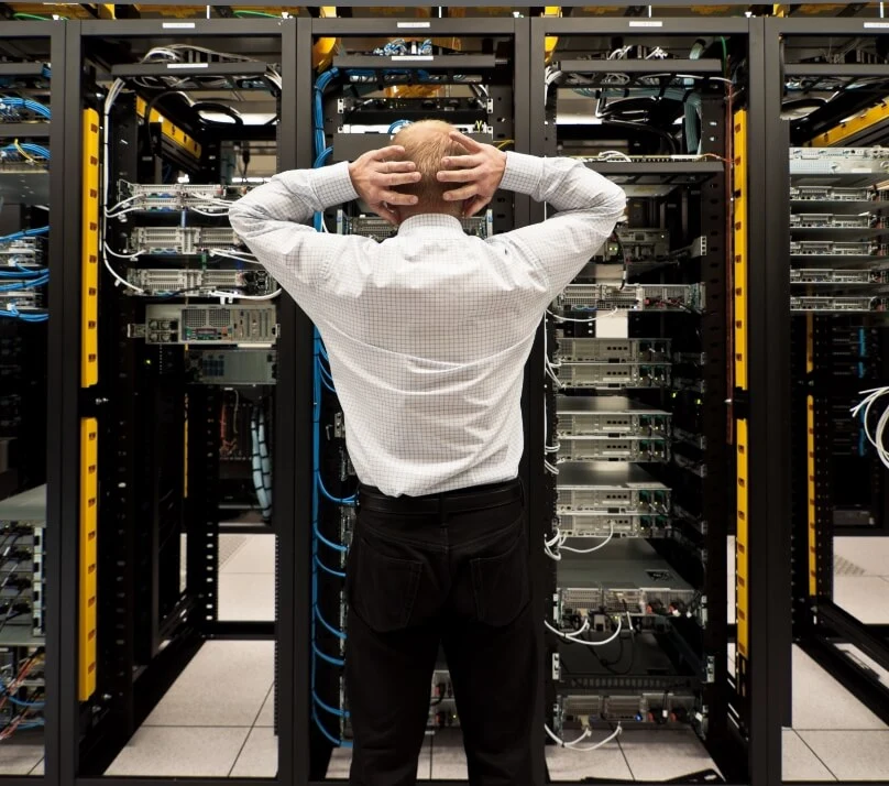 Man stands in front of server with hands clutching the back of his head.